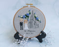A cross-stitched bride and groom next to an outlined church building. In the 